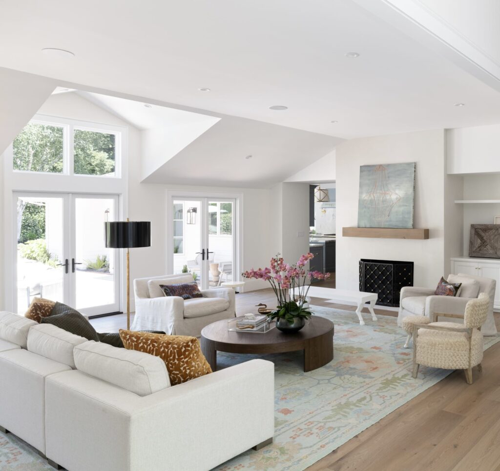 Light and airy modern living room featuring a handwoven Turkish Oushak rug in soft pastel tones, paired with neutral furniture, large windows, and elegant décor.