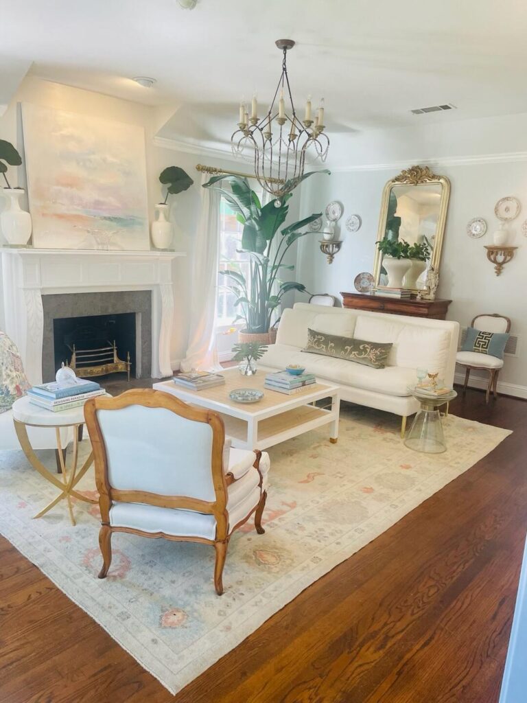 Bright and elegant living room featuring a soft-toned vintage Turkish Oushak rug paired with white furniture, gold accents, hardwood floors, and classic décor elements.