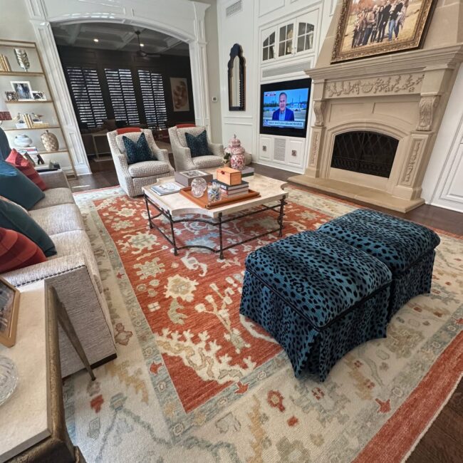 Beautiful living room featuring a vibrant Turkish Oushak rug with rich terracotta, blue, and cream tones, styled with classic furniture, a stone fireplace, and elegant home décor.